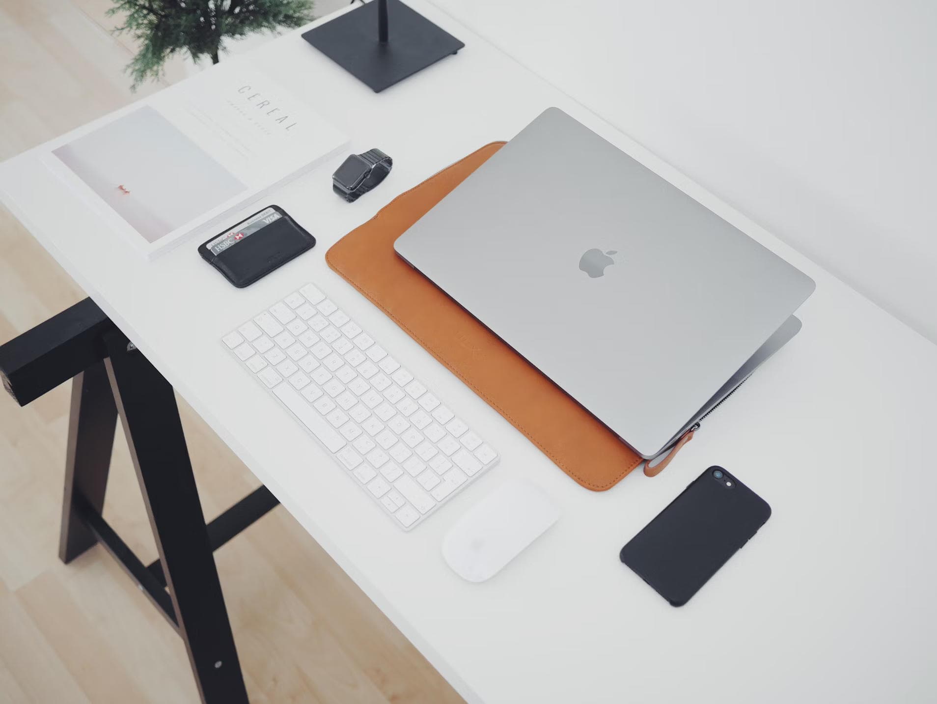 Bir ofis masası üzerinde dizüstü bilgisayar, klavye, fare, telefon, cüzdan, saat ve CEREAL isimli bir dergi.